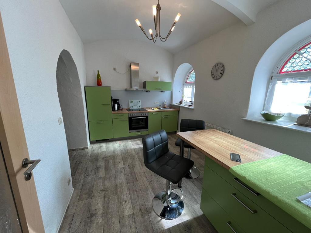eine Küche mit grünen Schränken und ein Schreibtisch mit Stuhl in der Unterkunft Grüne Villa in Kromlau