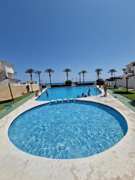 a large swimming pool with people in the water at Seafront Chalet Muchavista direct beach access in El Campello