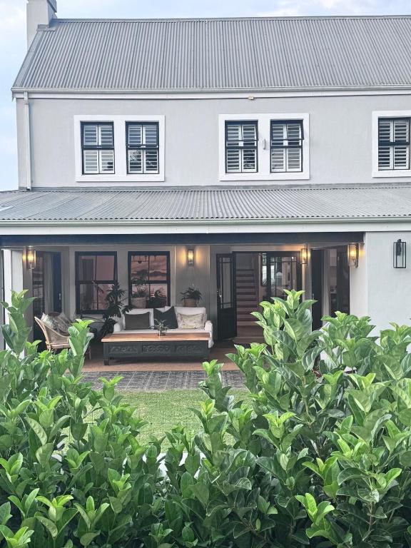 a white house with a porch with a couch at Dornoch House, Gowrie Village in Nottingham Road