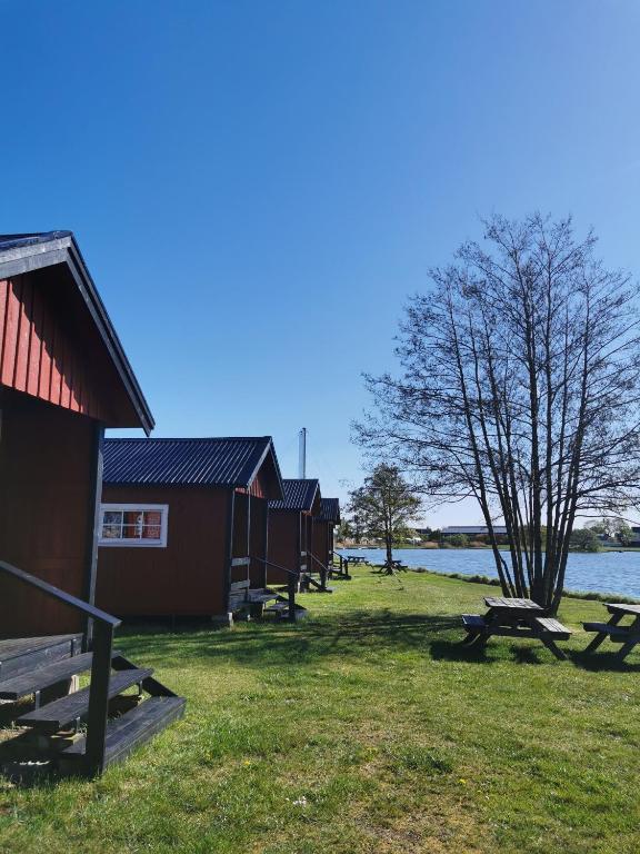 a row of huts next to a body of water at Stuga1-6 Dalskärs camping Badrum i Servicehus in Bergkvara
