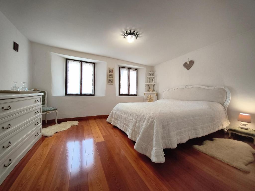 a bedroom with a bed and a dresser and two windows at La casa nel borgo in Cavaso del Tomba