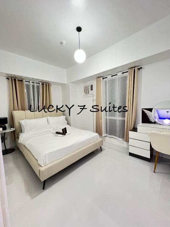 a white bedroom with a bed and a desk at Welcome to lucky7suites in Manila