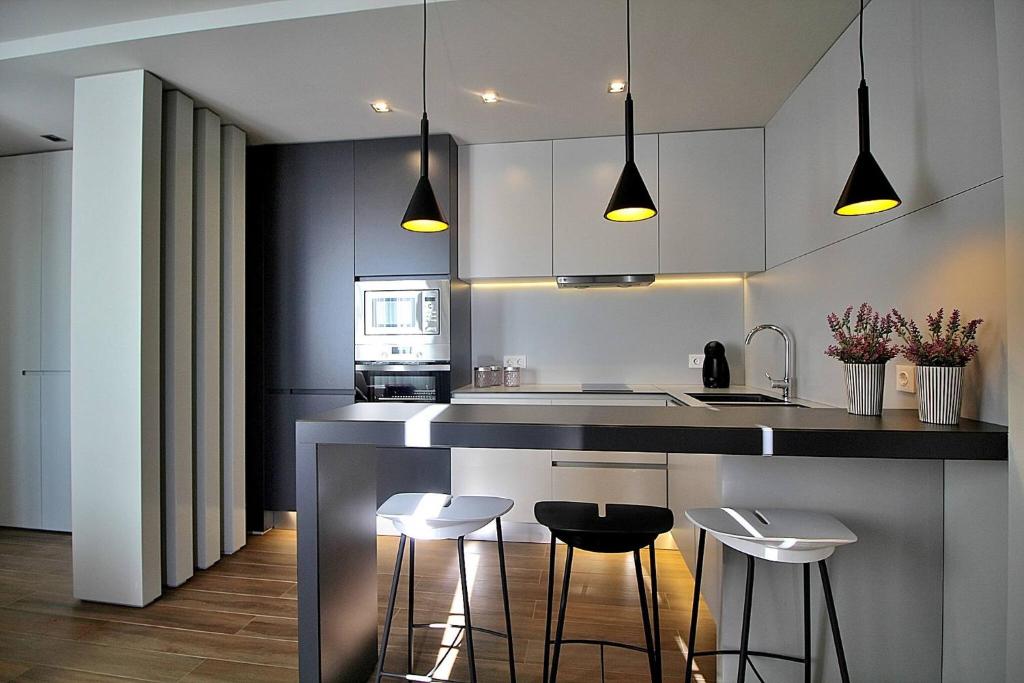a kitchen with white cabinets and black counter stools at RestOnDouro Oporto Flat in Valbom