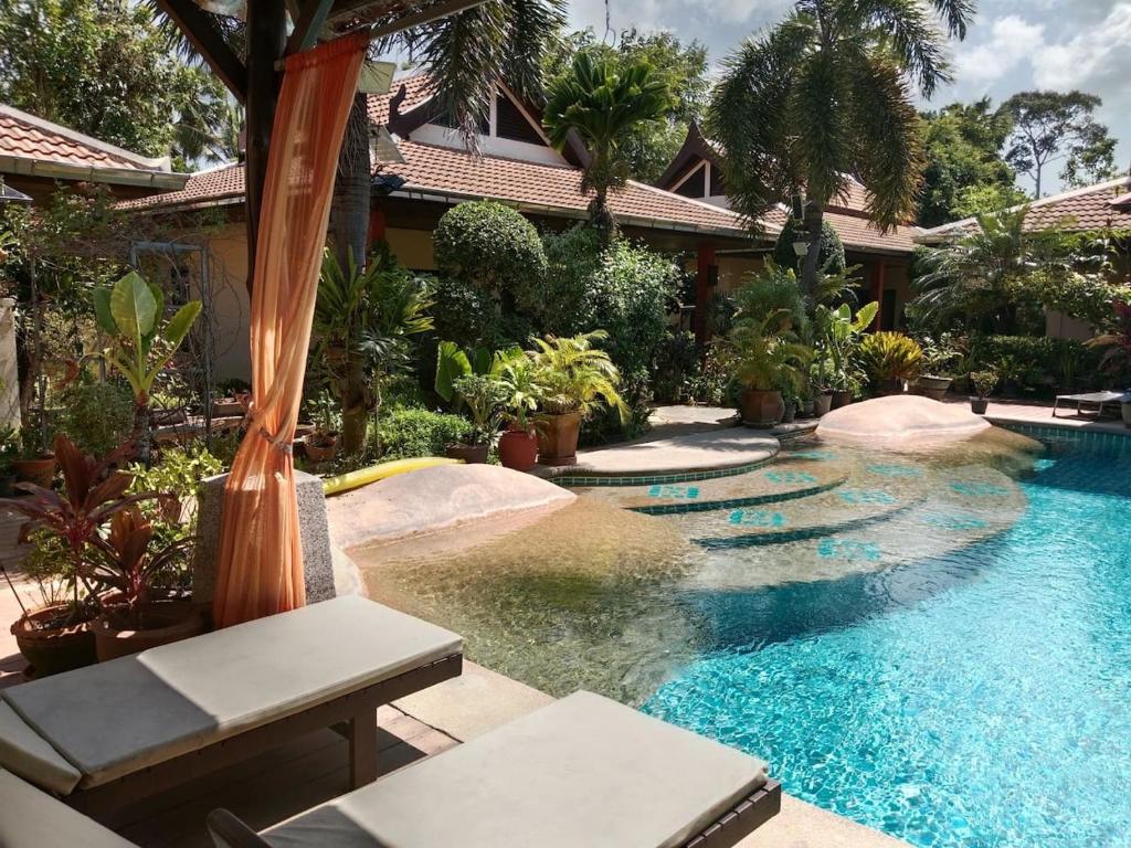a swimming pool in front of a house with trees at Baan Tropicana in Mae Nam