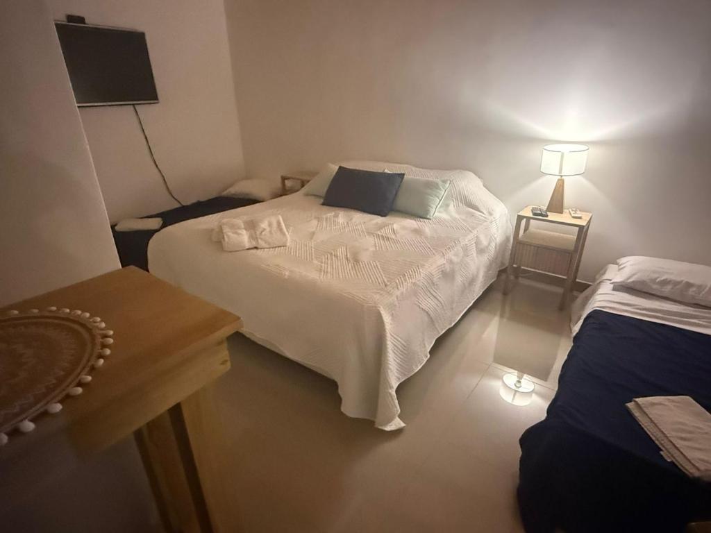 a small bedroom with a white bed and a table at Cocheras Ezeiza Victoria in Ezeiza