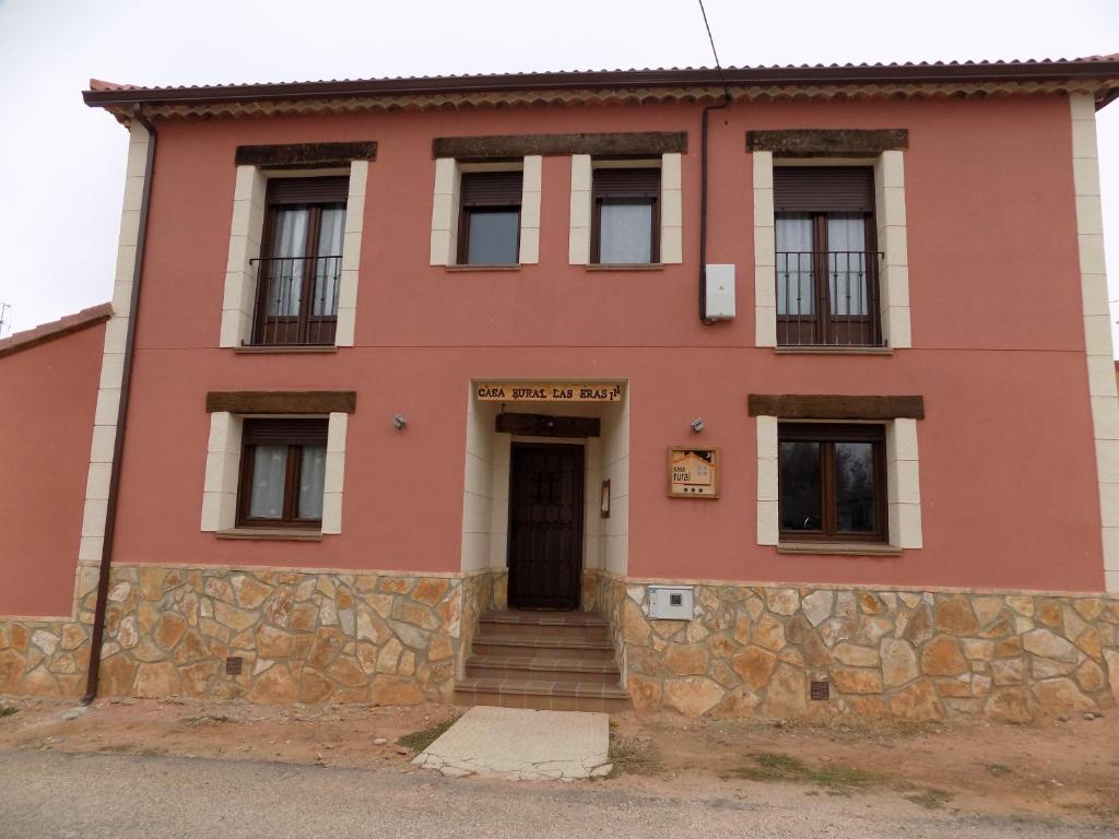 ein rotes Gebäude mit einer Steinmauer und einer Tür in der Unterkunft Casas Rurales las Eras III in Ayllón