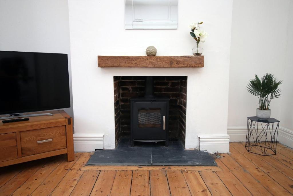 a living room with a fireplace and a tv at Cathedral House by Tŷ SA in Newport