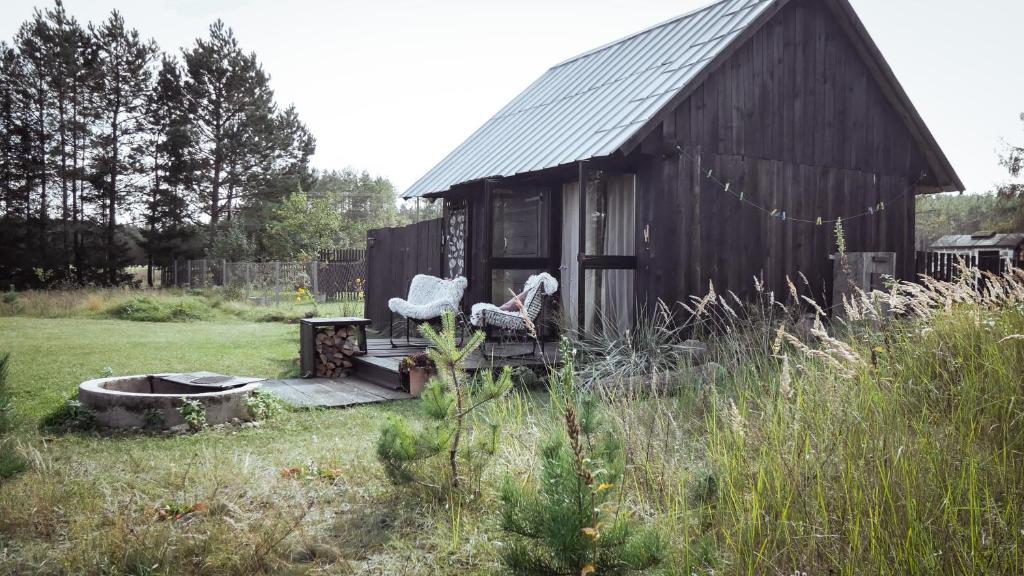 a house with a chair and a table in a field at Drewutnia nad Hańczą in Sernetki