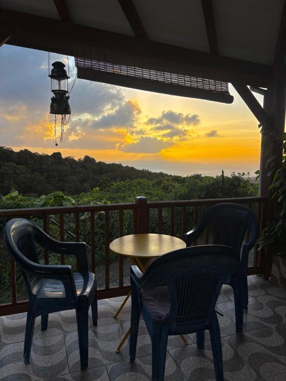 two chairs and a table on a balcony with a view at Versant Caraïbes in Gourbeyre
