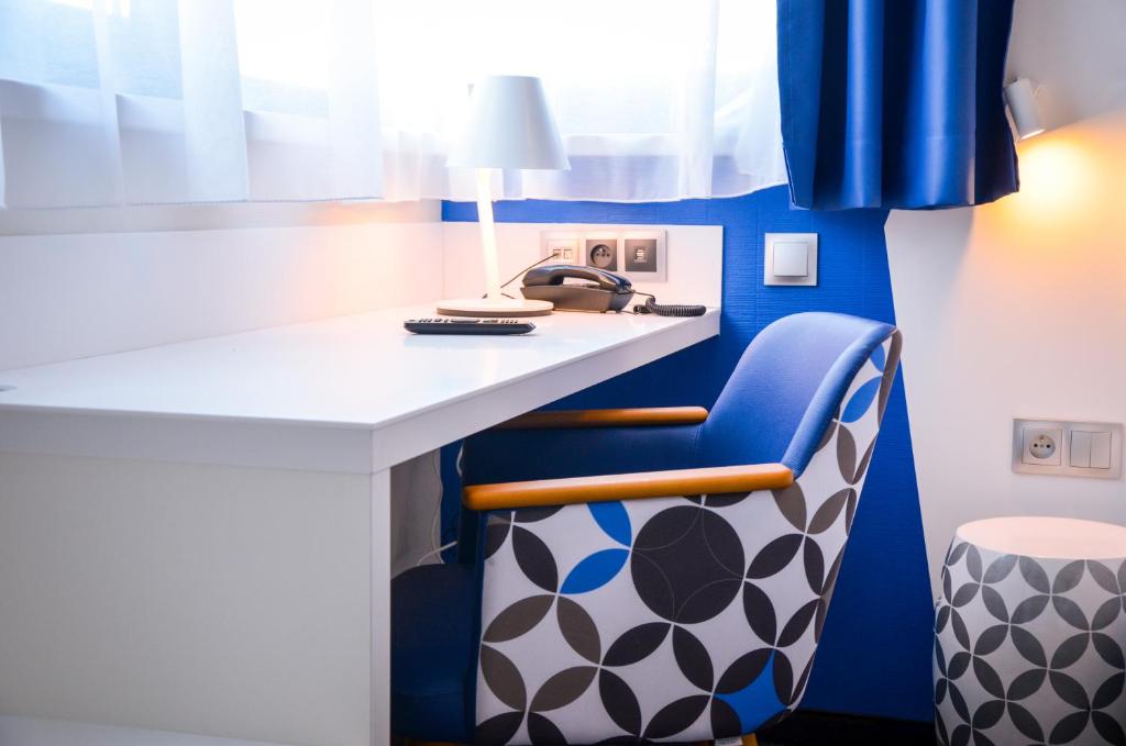 a blue and white room with a desk and a chair at Hôtel ORIGAMI in Strasbourg