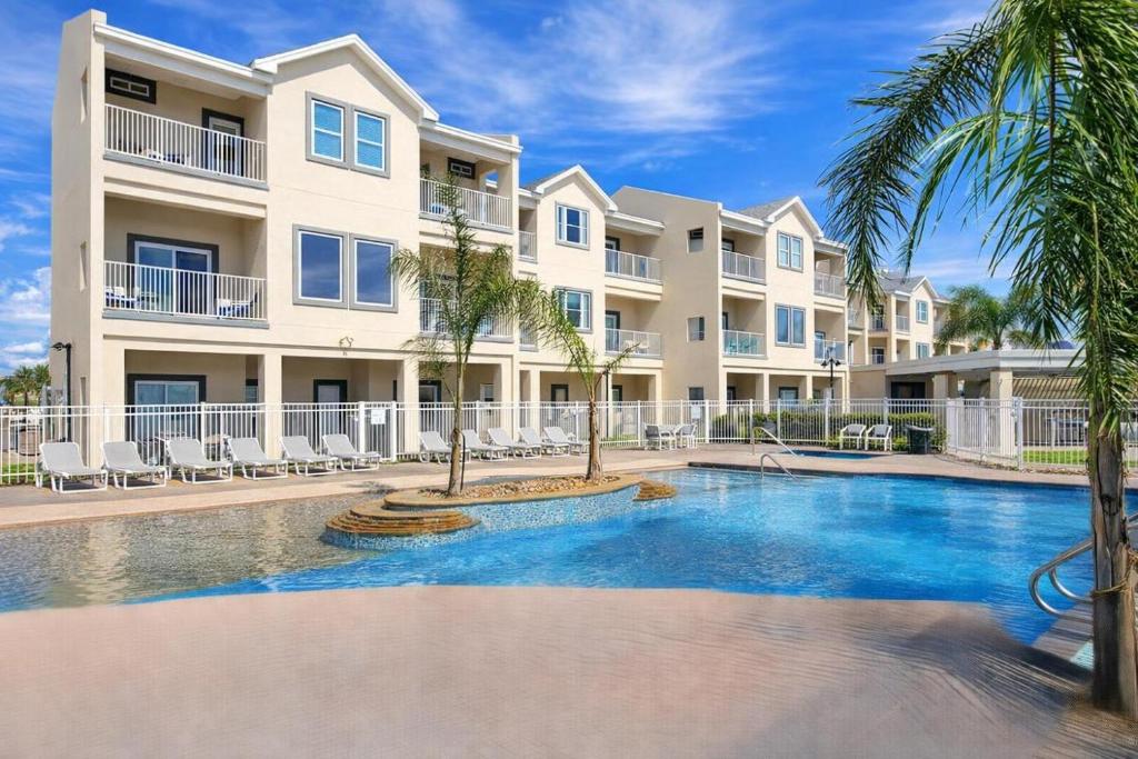 a swimming pool in front of a building with palm trees at 3 level luxury Beachlike Pool Killer Sunsets in South Padre Island