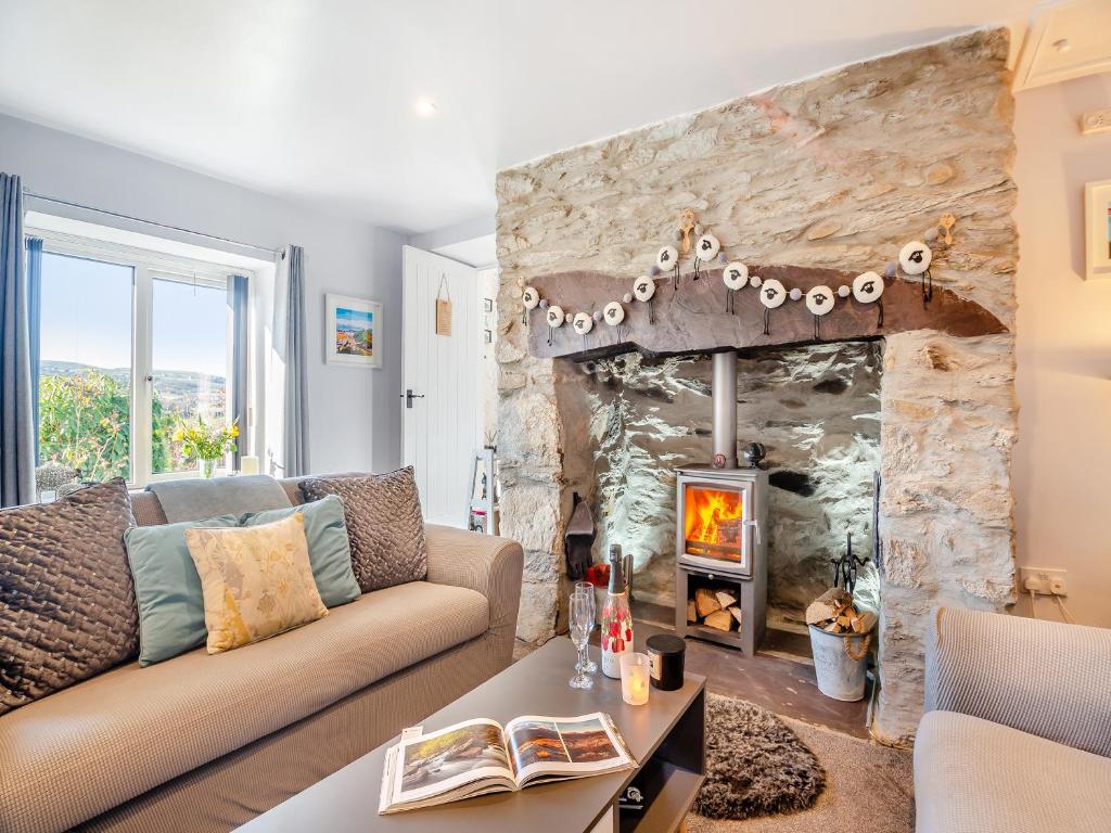 a living room with a couch and a stone fireplace at Hyfrydle Cottage in Talysarn