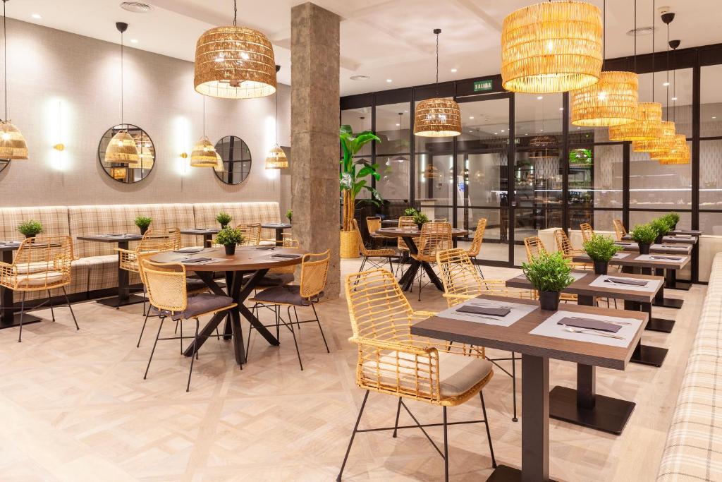 a restaurant with tables and chairs and chandeliers at THE APARTMENT by assethoteles in Torrejón de Ardoz