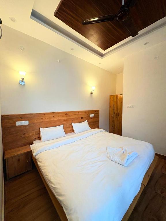 a bedroom with a large bed with white sheets at GJ Wellness And Stay in Rishīkesh