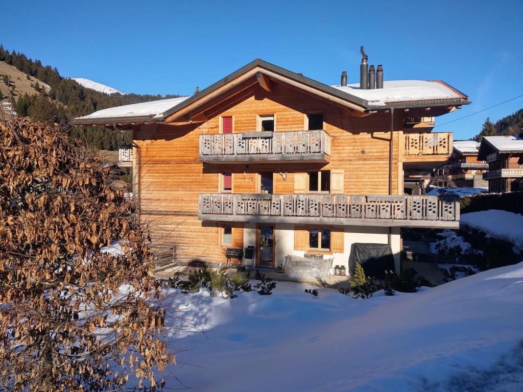 a log house with a deck in the snow at Le Charme 1, Morgins in Morgins