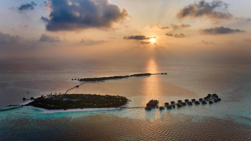 an island in the ocean with the sunset in the background at Conrad Maldives Rangali Island in Mandhoo