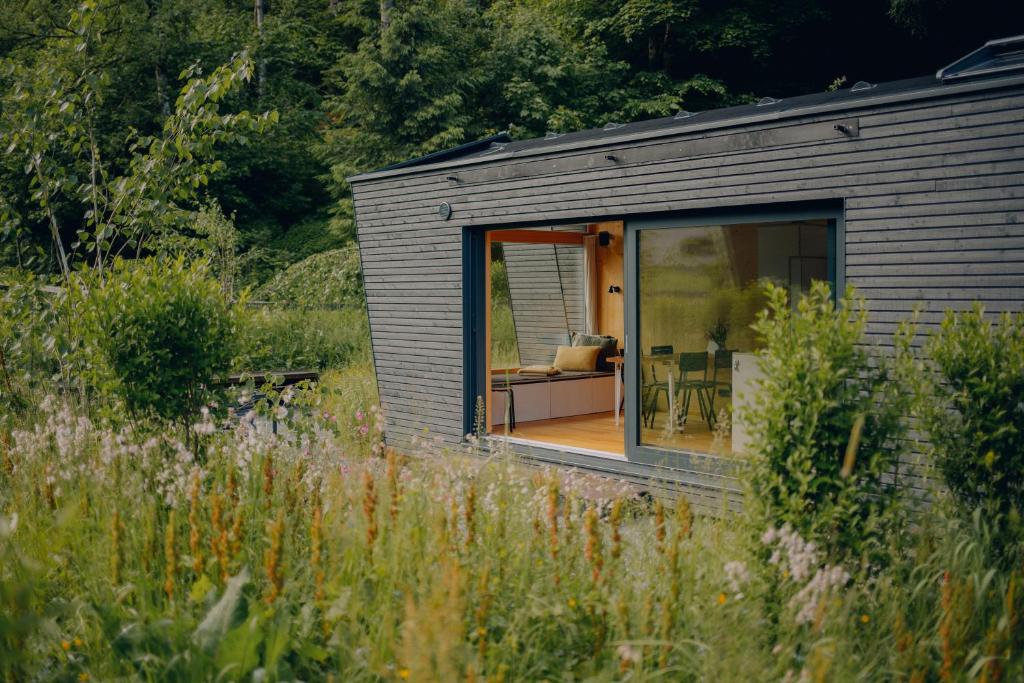 a small house with a large window in a field at cabinski Montafon in Sankt Gallenkirch