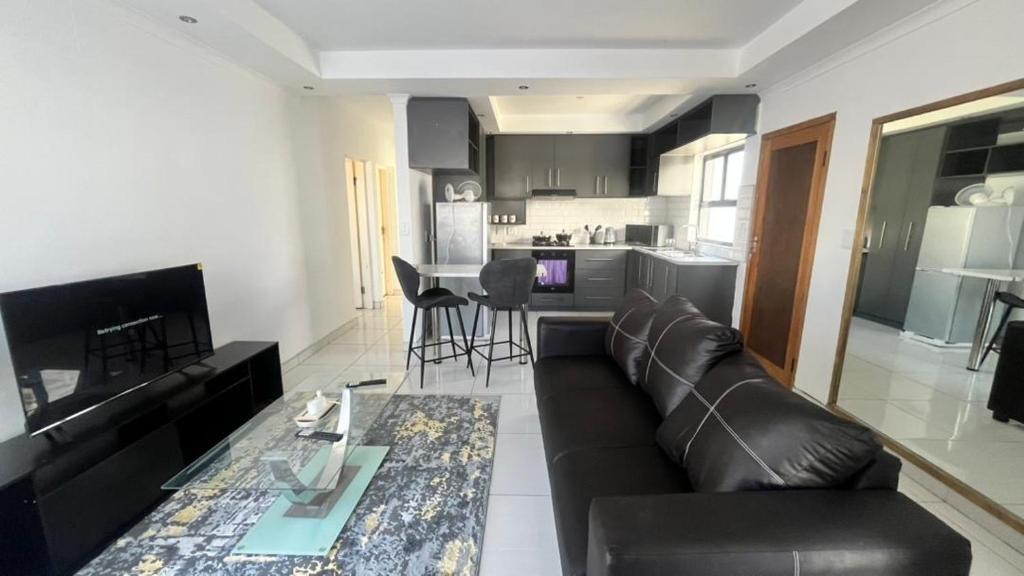 a living room with a black leather couch and a kitchen at CasaLisa beach House in Langstrand