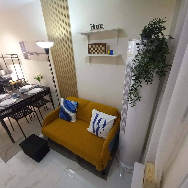 a living room with a yellow couch with two pillows on it at Tanza, Cavite Transcient House near SM in Tanza