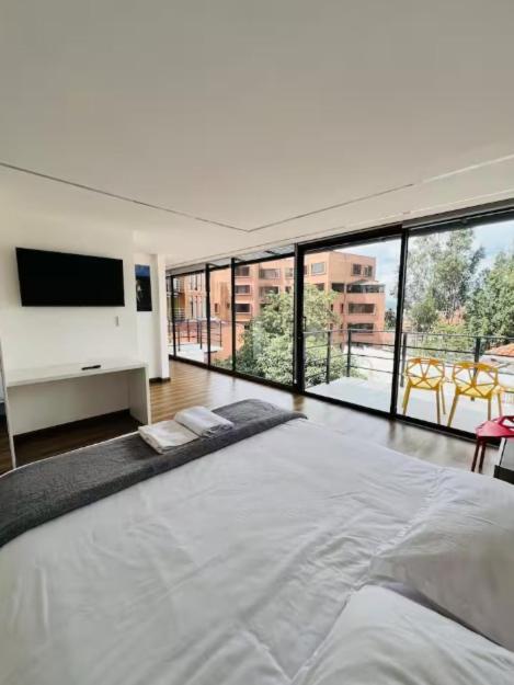 a large white bedroom with a large bed and a flat screen tv at Cuenca Hotel Apartment in Cuenca