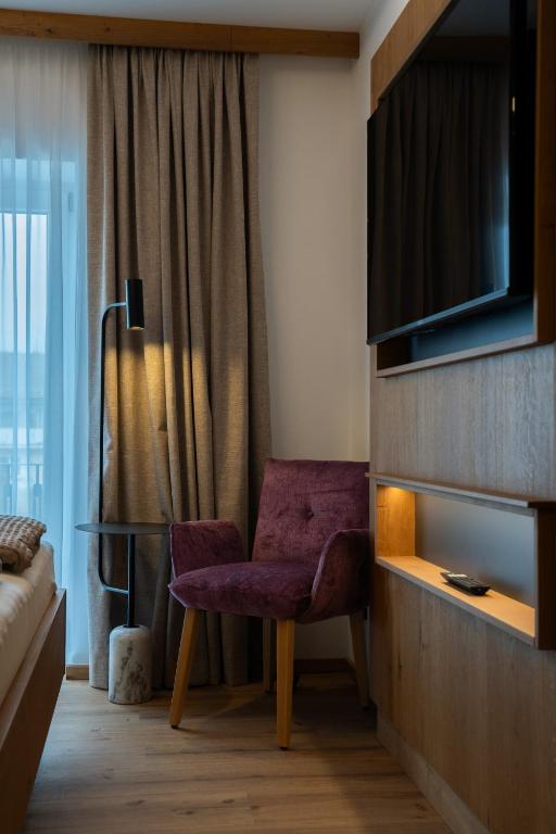 a living room with a purple chair and a television at Zenger Hotel in Offenberg