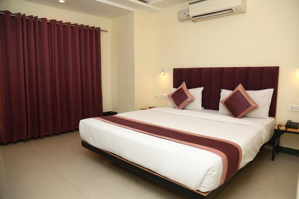 a bedroom with a large bed with red curtains at SoonStay Konark Inn in Indore