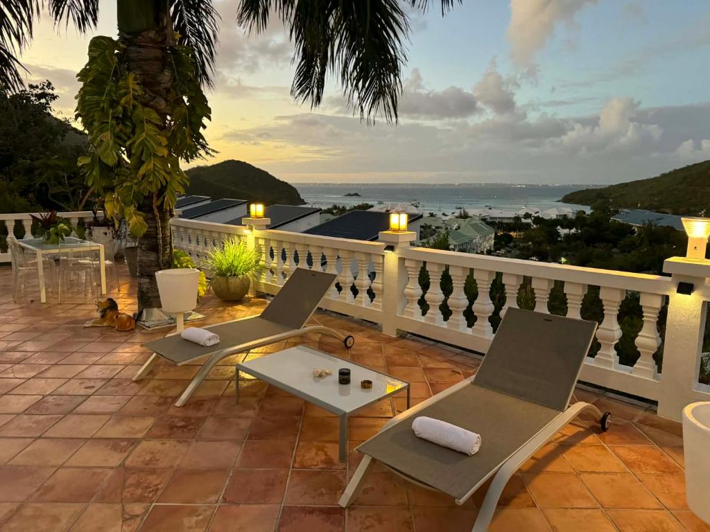 a balcony with chairs and a table and the ocean at Villa Joëlle in Anse Marcel 
