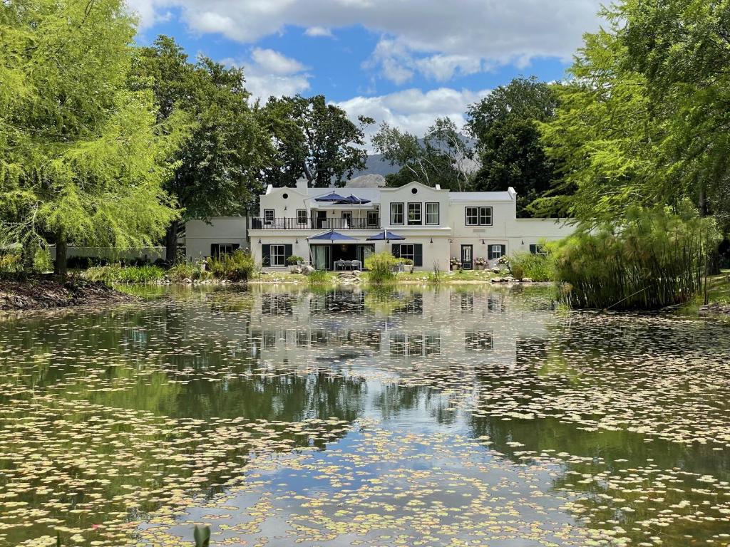 a white house with a pond in front of it at Klein Champagne Guesthouse and Cottages in Franschhoek