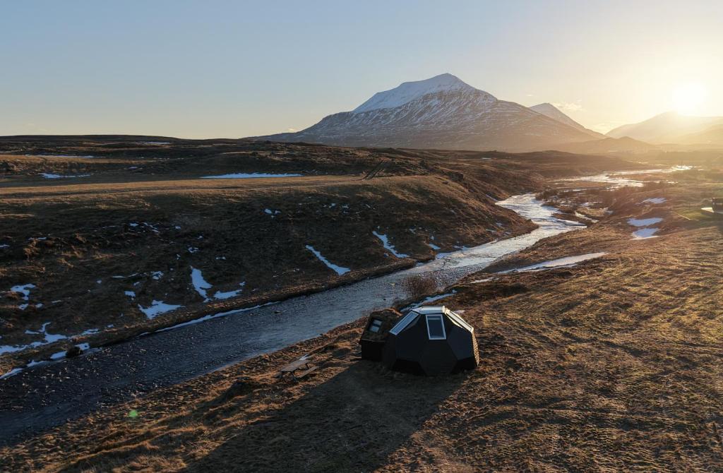 a tent in the middle of a field with a mountain at Igloo-Dome by a River - Sky Sighting - Glamping in Litli-Árskógssandur