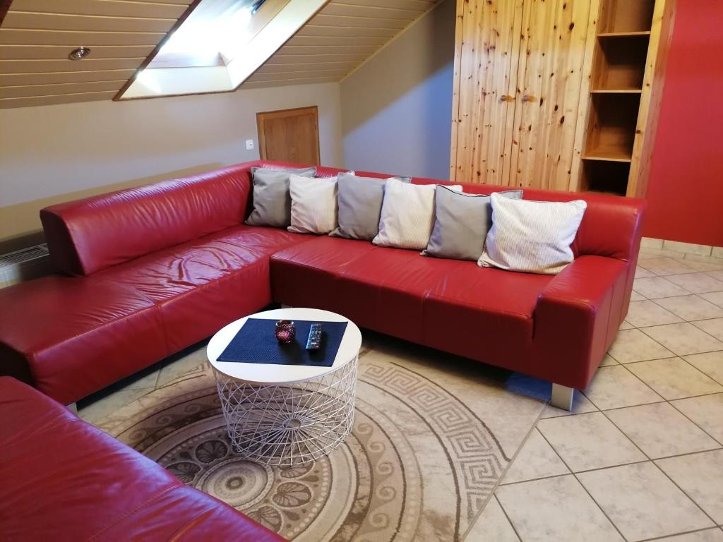 a red couch in a living room with a table at Lieblingsplatz in Ebersburg