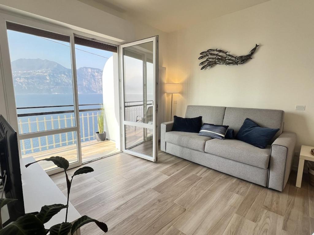 a living room with a couch and a large window at Sottovento Beths House in Brenzone sul Garda