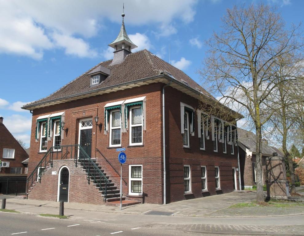 un bâtiment en brique avec une cloche au-dessus dans l'établissement Raadhuis Dinther Suites, à Heeswijk-Dinther