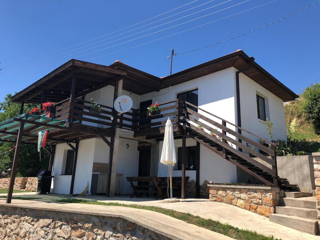 a white house with a umbrella and a table at Paradise - Guest House in Beden