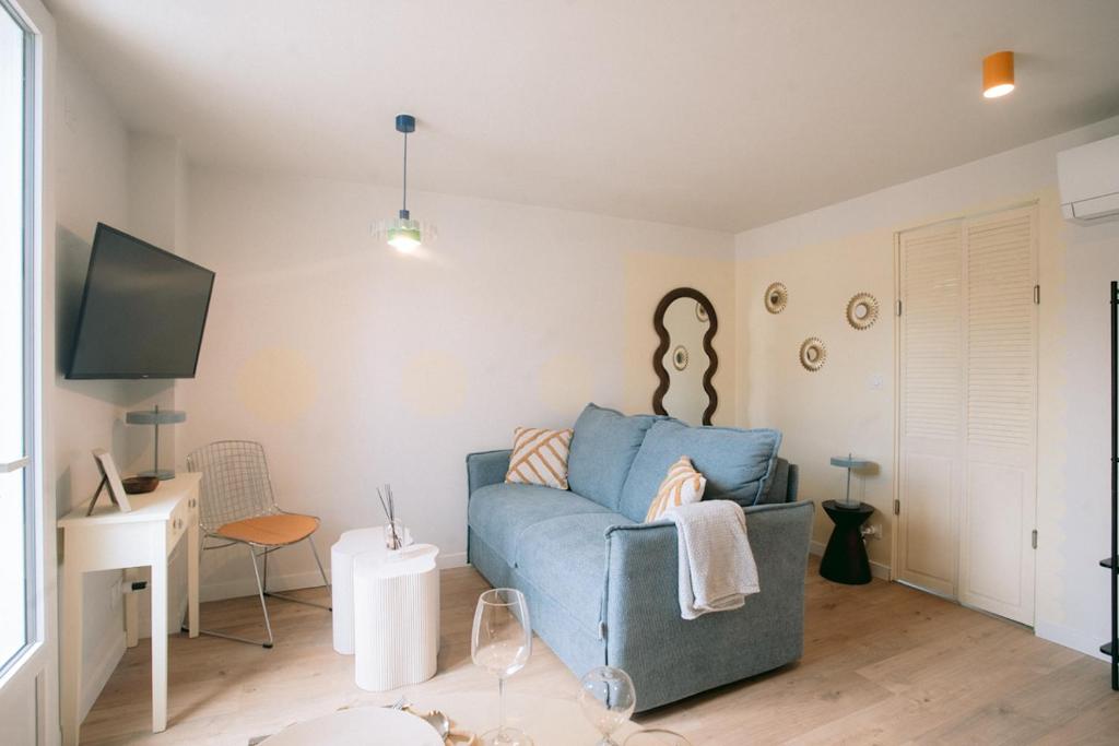 a living room with a blue couch and a tv at Les archives de Georges 153 - Appart' de standing en centre-ville - Balcon privé, Climatisation, Caméra de vidéo surveillance in Périgueux