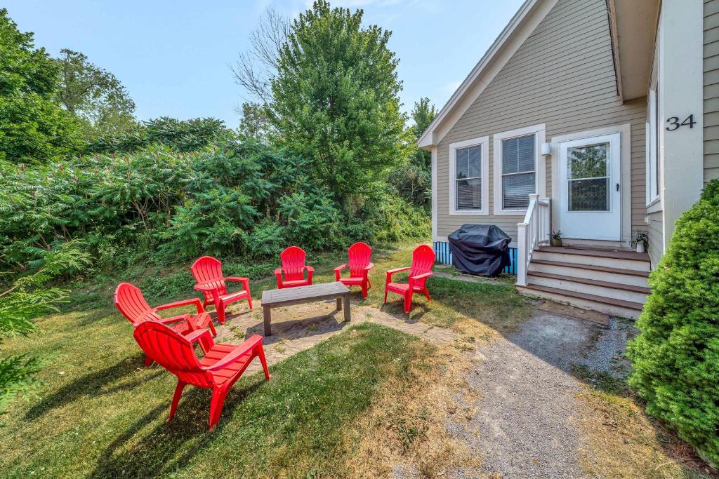 a group of red chairs and a table in front of a house at The Bluebird - 34 Meadow View in Cherry Valley