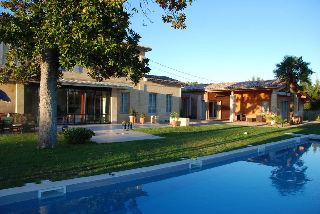 a house with a swimming pool in front of a yard at Les Ambèles in Saint-Magne-de-Castillon