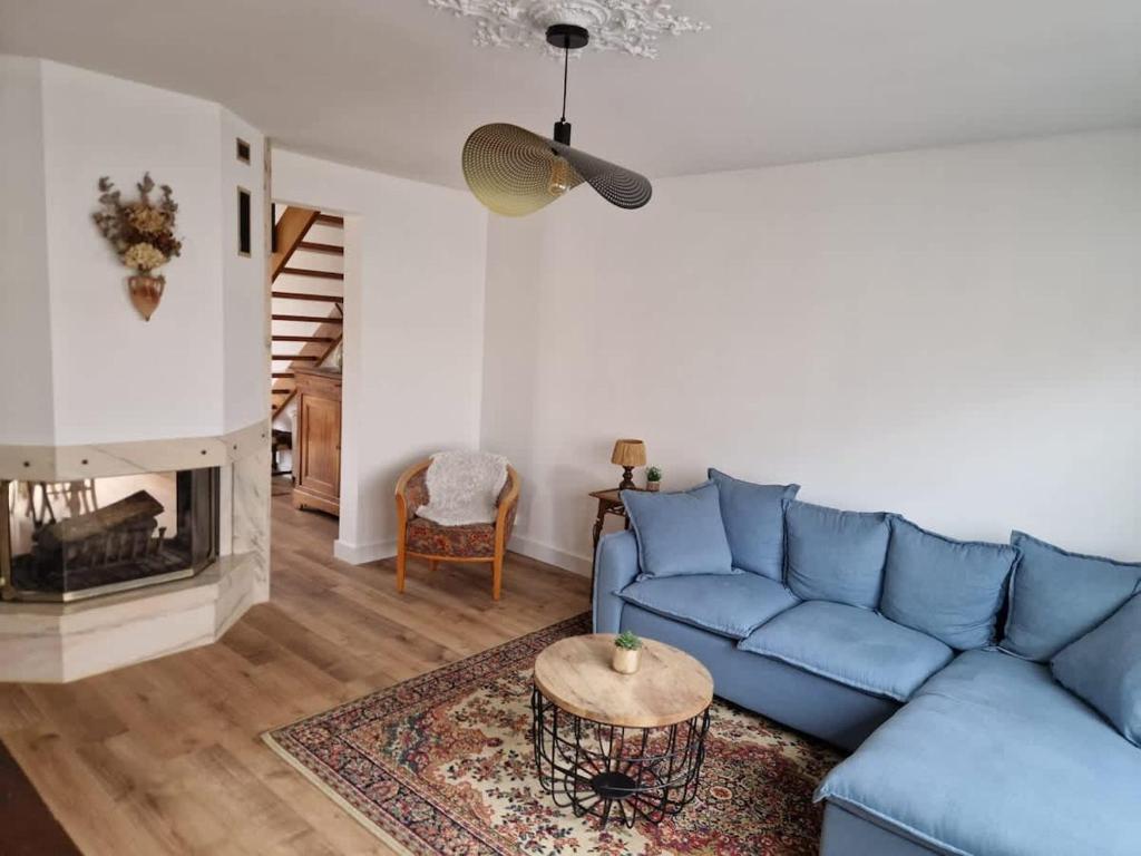a living room with a blue couch and a fireplace at La Maison Elegance & Charme in Marquise