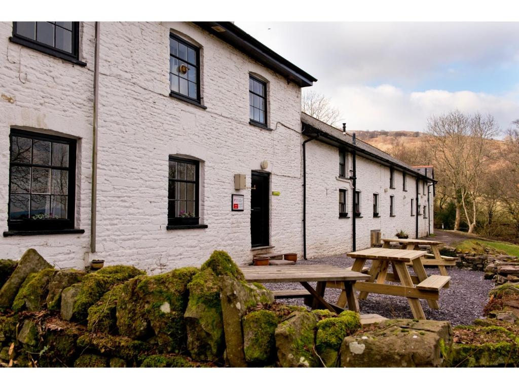 - une table de pique-nique devant un bâtiment blanc dans l'établissement YHA Brecon Beacons, à Brecon