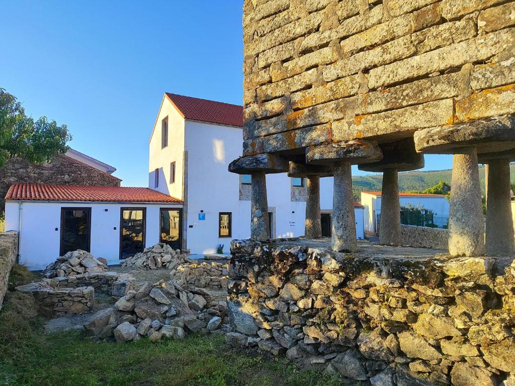 a building with a stone wall next to a house at Pensión A Lubre in Fisterra