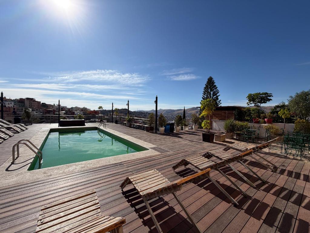 a swimming pool with lounge chairs next to a wooden deck at Hotel 1988 Guanajuato in Guanajuato