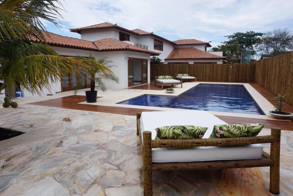 a villa with a swimming pool in front of a house at Villa Ferradura Mar in Búzios