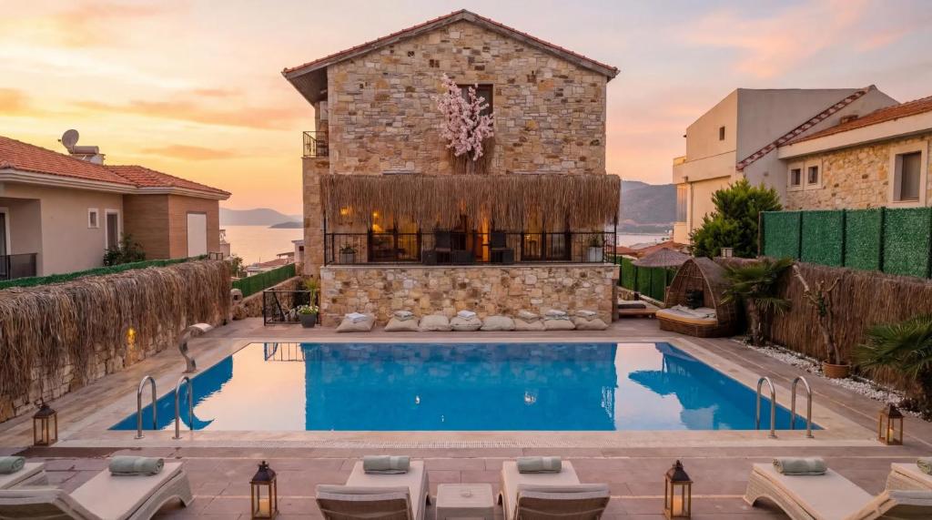 a villa with a swimming pool in front of a building at Stone House Foça Otel in Yenifoça