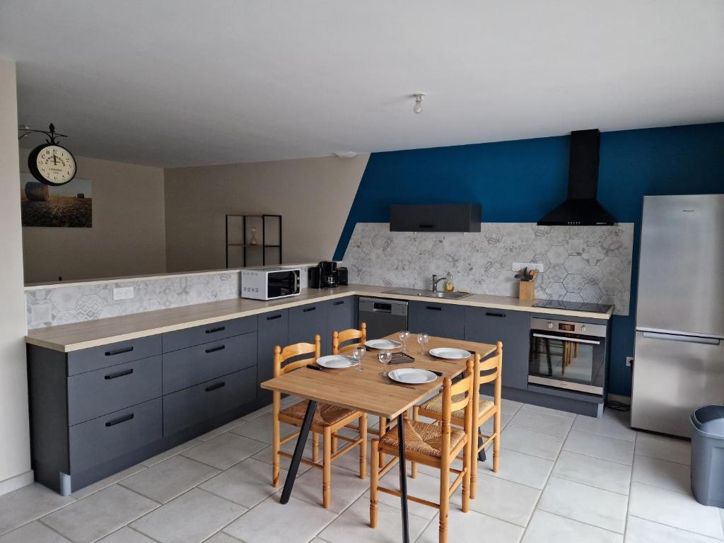 a kitchen with a wooden table and blue cabinets at La maison du Lac in Louin