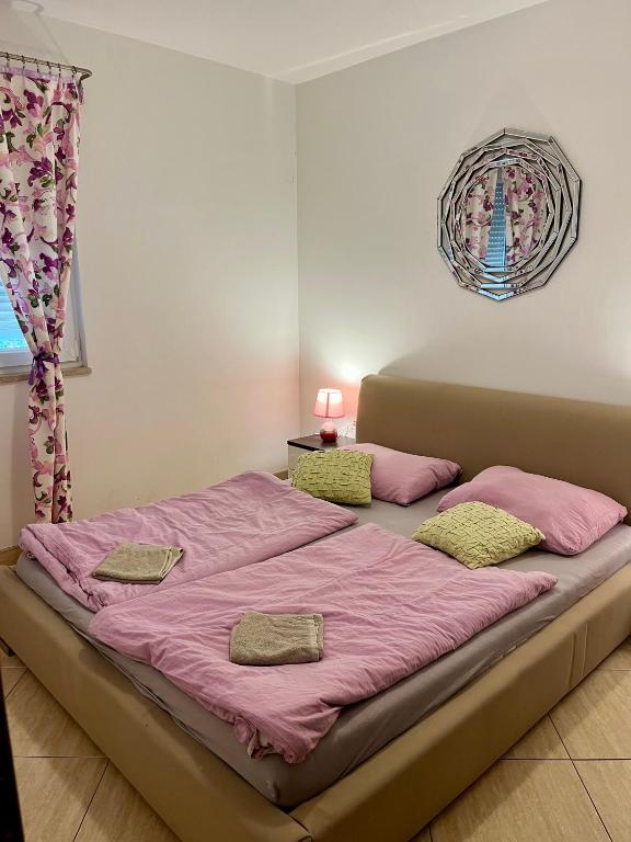 a large bed with pink sheets and pillows on it at Hostel **Casa del Sole** in Klenovica