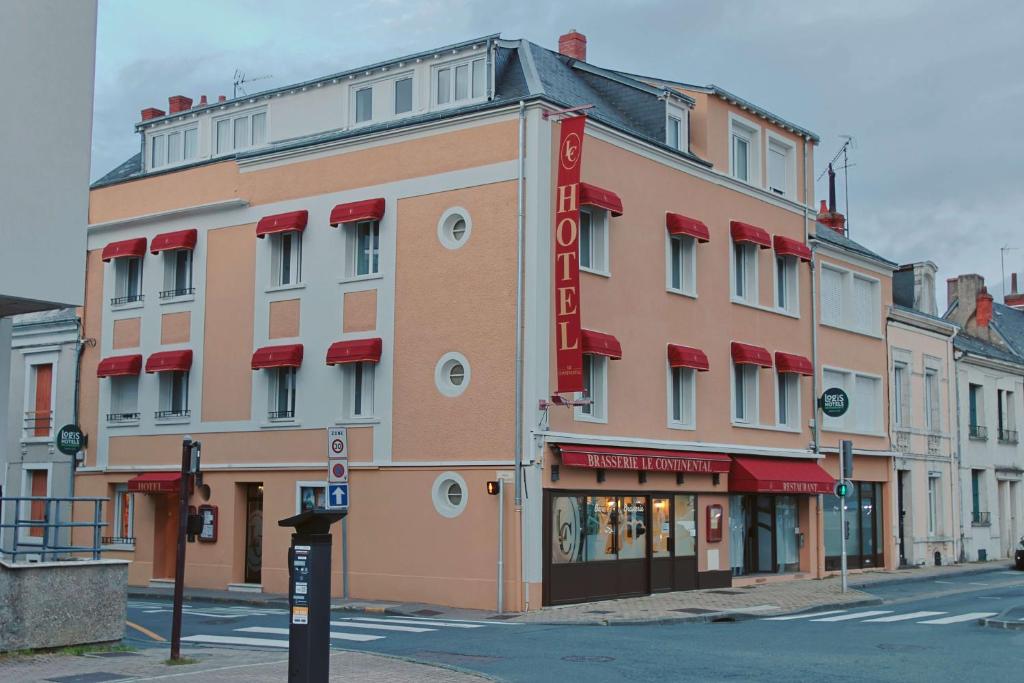 a building with a red sign on the side of a street at Logis Hôtel Restaurant Le Continental in Châteauroux