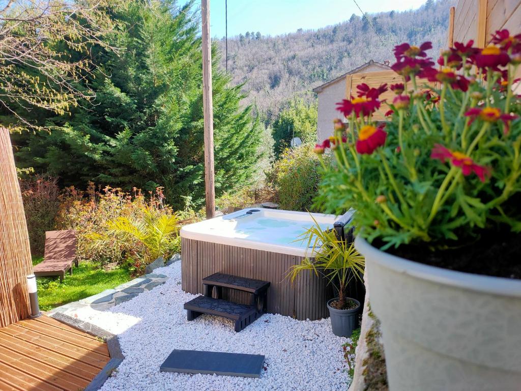 a hot tub in a garden with flowers in a pot at Maison Corse avec SPA - La Casa Serena in Ortiporio