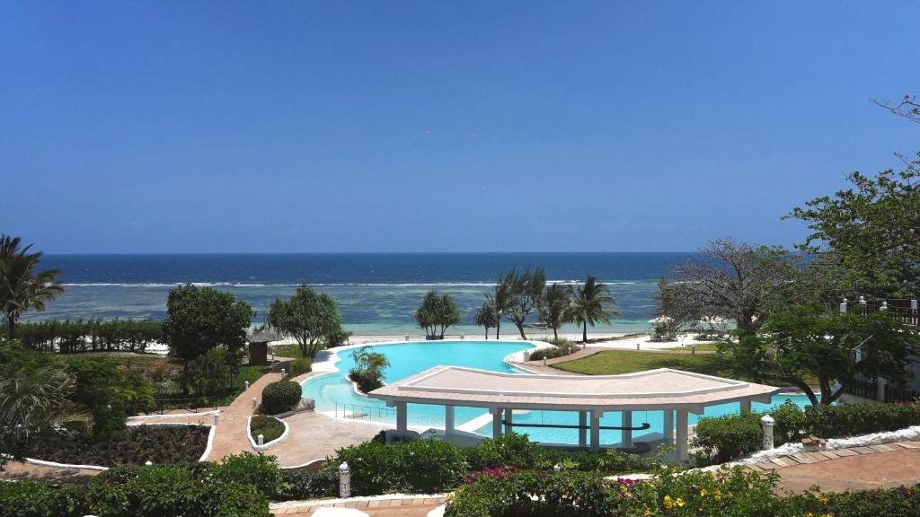 a swimming pool with a gazebo and the ocean at Zahari Oceanfront in Msambweni
