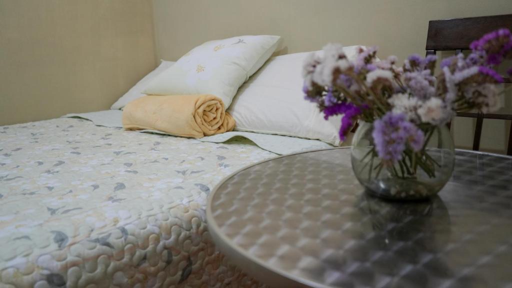 a vase of flowers sitting on a table next to a bed at Hostal Aurora a 3 cuadras de la Plaza de Armas in Cajamarca