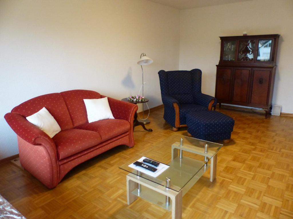 a living room with a red couch and two chairs at Ferienwohnung Asenberg in Bad Salzuflen