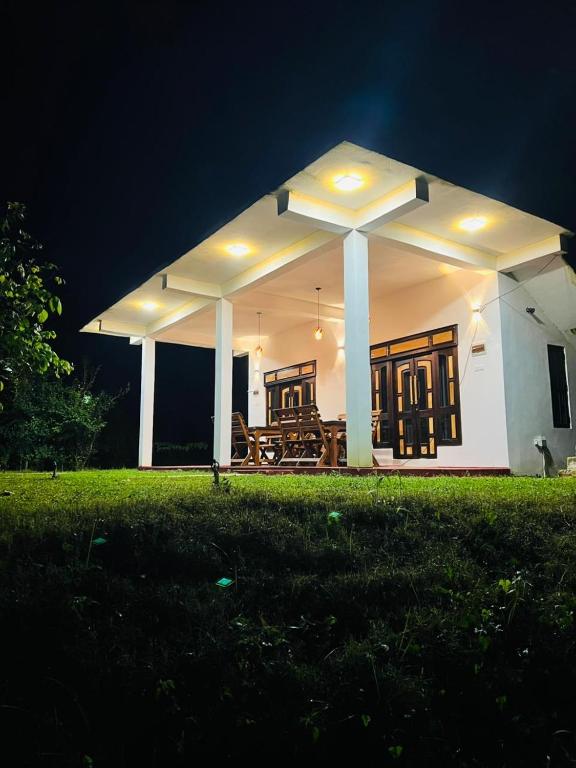 a white house with a patio at night at Flora Lake View Resort Wilpattu in Wilpattu